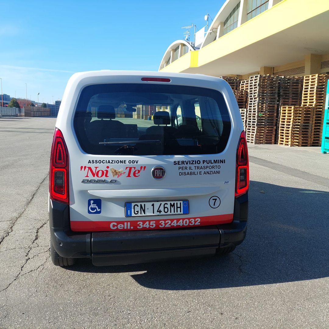 Il retro di un pulmino con il logo Noi per Te, il simbolo della carrozzina e il numero di telefono