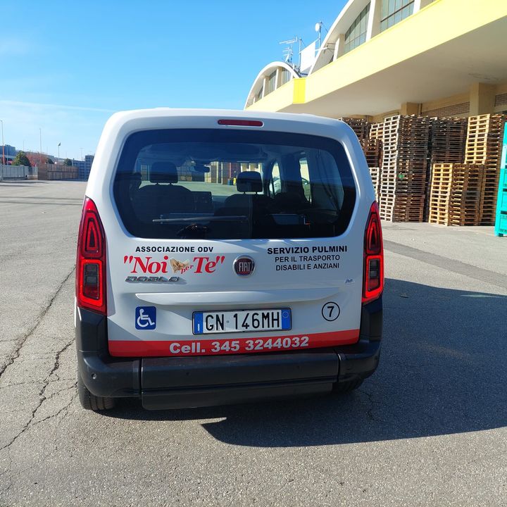 Retro di un pulmino con il logo Noi per Te, il simbolo della carrozzina e il numero di telefono
